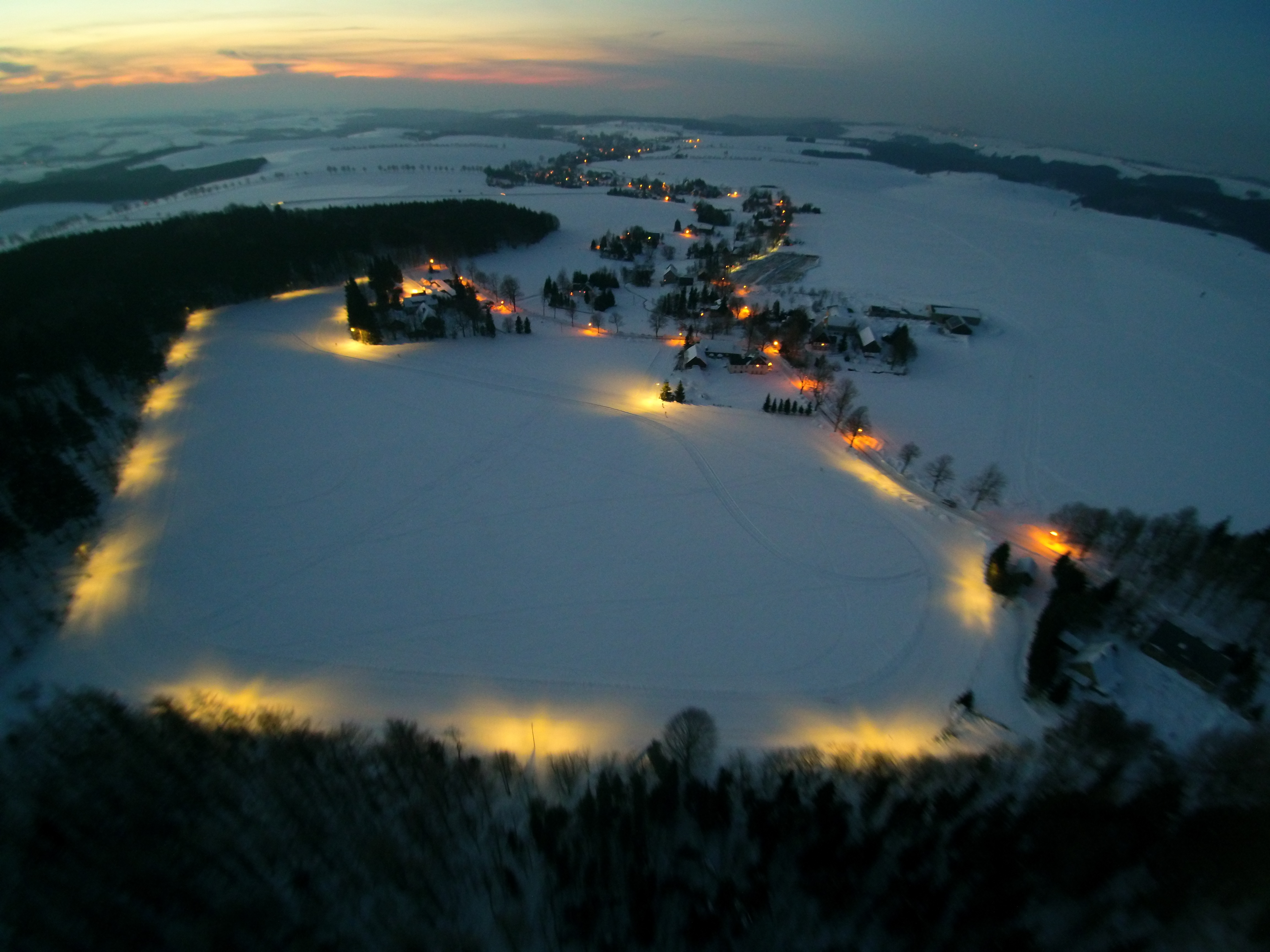 Eine zugeschneite Wiese bei Nacht, beläuchtet von oben Fotografiert. 