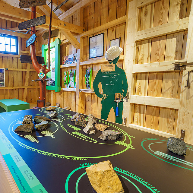 Ein Raum mit verschiedenen Informationspunkten rund um den Geopark. Zu sehen zum Beispiel Gestein.