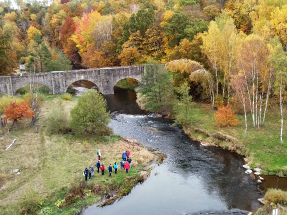 Fluss schlängelt sich durch eine Steinbrücke und ringsherum Herbstlandschaft.